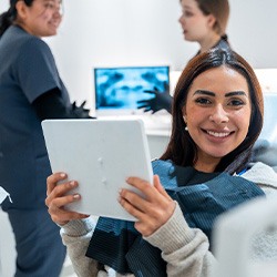 Patient smiling while holding mirror in treatment chair