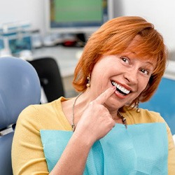Patient pointing to her new dental implant restoration