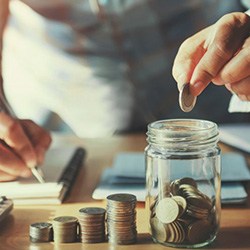 Man dropping a coin into a glass jar