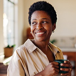 Woman smiling while drinking coffee at home