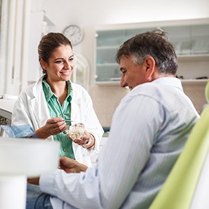 Smiling dentist talking to patient in treatment chair