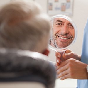 Man smiling at reflection in small mirror