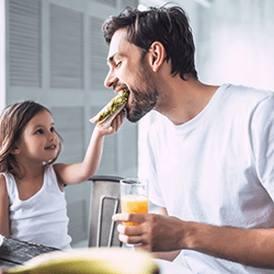 a father with dental implants eating with his daughter
