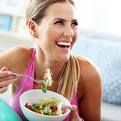 a woman smiling and eating with dental implants 