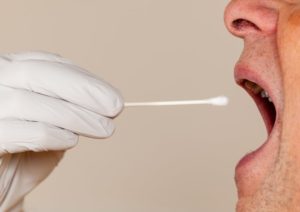 man with mouth open cotton swab