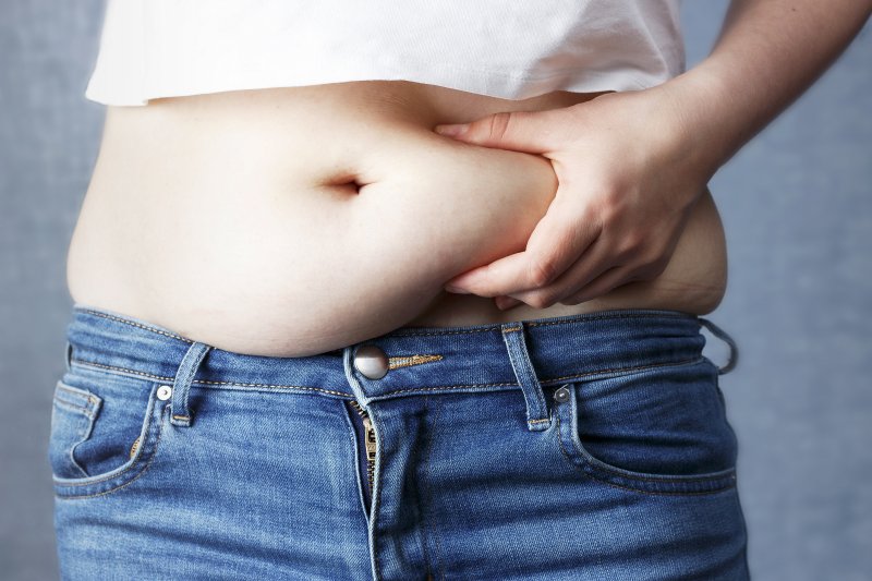 Close-up of overweight person holding their belly