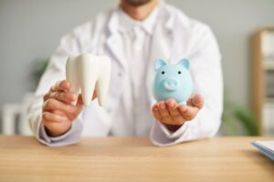 Man holding a tooth replica and piggy bank